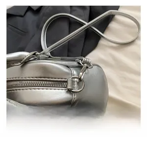 Close-up of the silver shell bag showing metallic finish, zipper and strap hooks