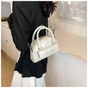 Detail of cream metallic shell bag with bow decor shown on model for size perspective