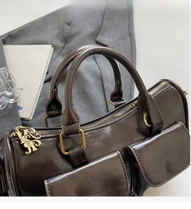 Detail of dark brown leather handbag with gold zipper charms and sturdy handles