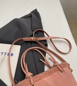 Gros plan d'un sac cabas rose en polaire avec bandoulière en cuir et boucle dorée