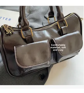 Detail of dark brown boston bag with dual pockets and vintage golden metal hardware