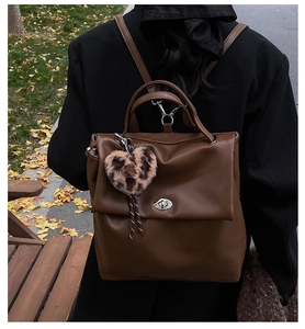 Rückansicht brauner Lederrucksack mit Leoparden-Herzanhänger in herbstlicher Straße