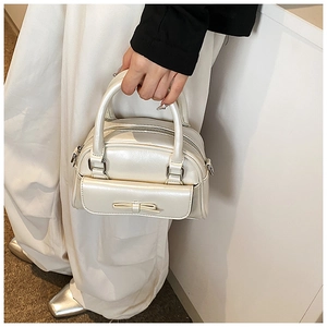 Detail of pearlescent beige Boston handbag with bow decoration and metal zipper
