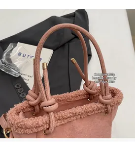 Détail du sac à main rose en daim avec bordure en peau lainée et poignée à nœuds design