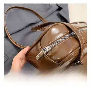 Close-up of brown glossy leather bag with white contrast stitching and silver zipper