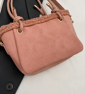 Gros plan sur un sac seau rose en daim avec bordure en laine et œillets dorés
