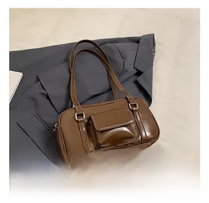 Detail of a vintage dark brown glossy shoulder bag featuring a front pocket and dual handles