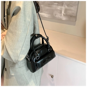 Detail of black faux leather Boston bag with bow accent and silver zipper hardware