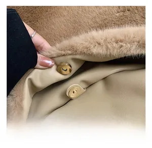 Detail van de gouden magneetsluiting op een pluchen camelkleurige imitatiebonttas