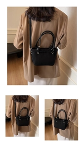 Detail of black matte crossbody bucket bag with faux fur trim and leather handles