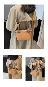 Detail of brown suede bucket bag with plush trim held by a model in a trench coat