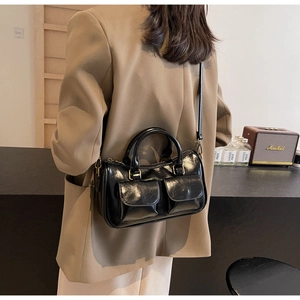 Detail of a black high-gloss Boston bag with double front pockets and gold hardware finish