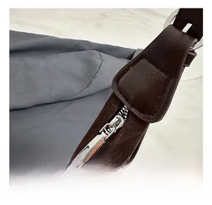 Detailed macro shot of silver metal zipper and reinforced stitching on dark brown leather bag