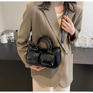 Detail of black crossbody bag featuring dual front pockets and vintage metal hardware