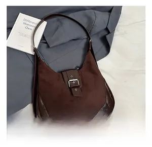 Detail of vintage brown suede hobo bag placed on grey blazer and white bedding