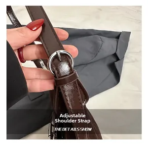Detail view of the adjustable strap and silver metal buckle on the dark brown leather tote bag