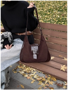 Outdoor shot of a vintage dark brown matte leather tote bag on a wooden bench