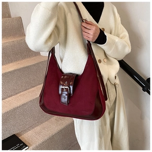 Detail of burgundy suede and glossy leather underarm bag with silver metallic buckle