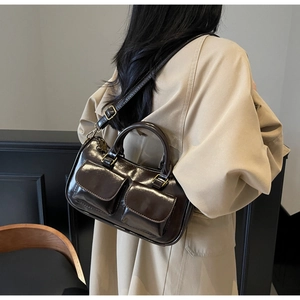 Detail of vintage dark brown glossy leather crossbody bag with dual front pockets and gold hardware