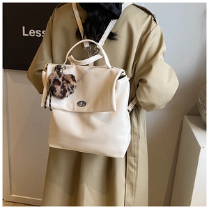Detail eines cremeweißen PU-Lederrucksacks mit Metalldrehverschluss und Leopardenherz