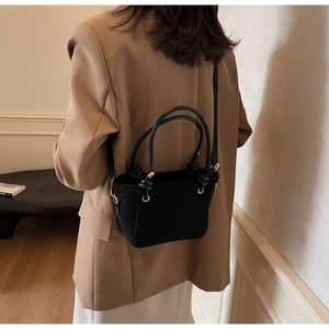 Detail of black crossbody bucket bag with matte texture and faux fur trim for autumn