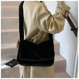 Moderne zwarte schoudertas van nepbont gedragen met een beige trenchcoat in een minimale setting