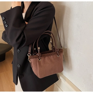 Close-up of dark brown suede bucket bag with plush faux fur trim and gold hardware