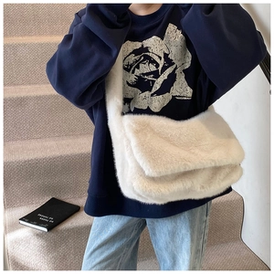 Witte crossbodytas van imitatiebont gestyled met een casual outfit op een trap