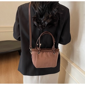 Detail of vintage brown suede crossbody bucket bag with warm faux shearling trim accents