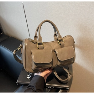 Detail of khaki barrel bag featuring double front flap pockets and vintage bronze hardware