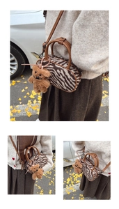 Détail du sac boston à motif zèbre avec lanières en cuir marron et breloque ours