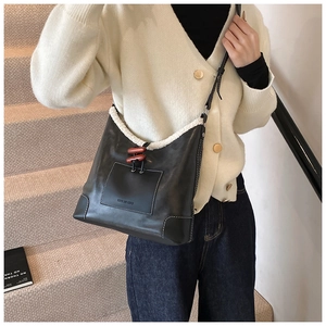 Detail of black leather bag with white faux fur trim and wooden horn buttons close-up