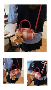 Détail du sac bowling en tweed à carreaux rouge et beige avec un porte-clé ours