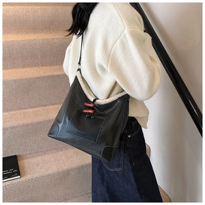 Detail of faux fur trim and wooden toggle closure on black leather shoulder bag