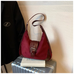 Details der burgunderroten Wildleder-Satteltasche mit Silberschnalle auf einem Koffer