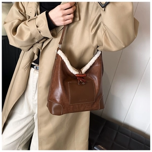Detail der braunen Vintage-Beuteltasche mit weißem Webpelzbesatz und Holz-Knebelverschluss