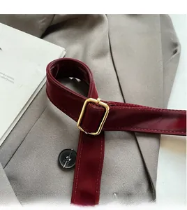 Detail of dark red leather strap featuring a square golden adjustable metal buckle