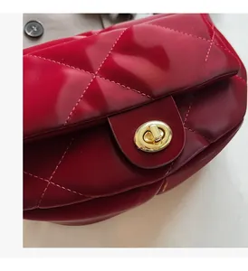 Close-up of a red quilted leather handbag featuring a golden oval metal twist lock clasp