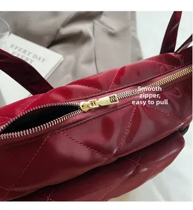 Detail of smooth gold zipper on burgundy quilted patent leather saddle bag