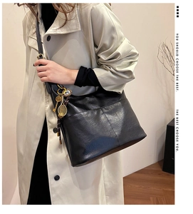 Détail du sac cabas noir avec pendentif raquette de tennis dorée et cuir texturé