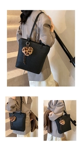 Detail of black woven tote bag with heart-shaped leopard print charm and long fringe