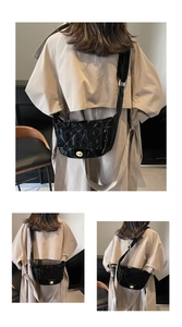 Detail view of the black quilted crescent bag with polished finish and gold clasp
