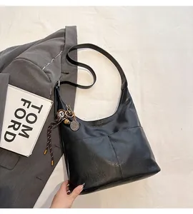 Détail du sac hobo en cuir noir avec un pendentif raquette de tennis et une fermeture éclair