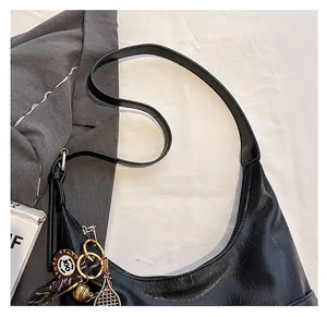 Détail du sac cabas demi-lune noir avec texture grainée et pendentif de raquette de tennis