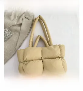 Détail macro du sac matelassé beige avec texture douce à carreaux et double anse