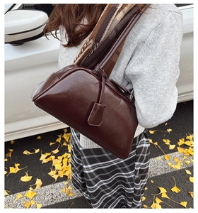 Retro dark brown leather Boston bag styled with an autumn outfit and yellow ginkgo leaves