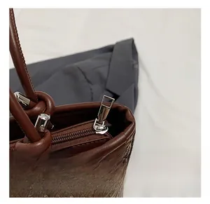 Close-up of silver metal zipper and woven texture on brown leather tote bag