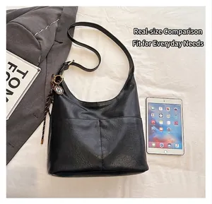 Détail du grand sac cabas en cuir noir comparé à un iPad et un magazine pour la taille