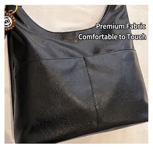 Détail du sac cabas en similicuir noir avec deux poches avant et accessoires dorés