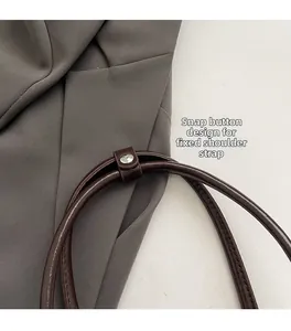 Close-up of dark brown leather shoulder strap with silver snap button and smooth edges